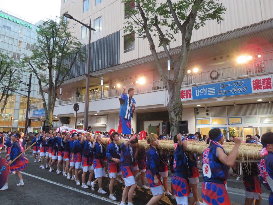 大勢の人数で担がれた巨大なわらじの上に市長が立っている写真