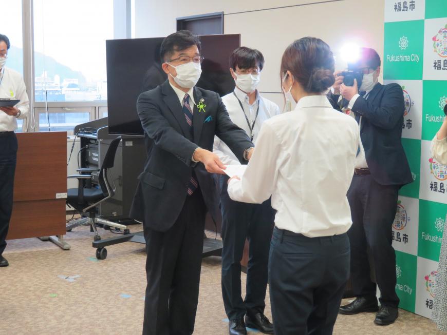 市長が女性職員に辞令交付しているところを職員後方から撮影した写真