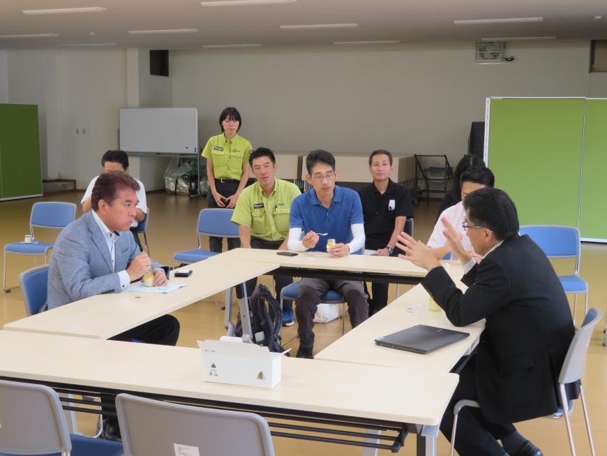 ロの字型に並べられた机に参加者が座り、市長と男性が話をしている写真