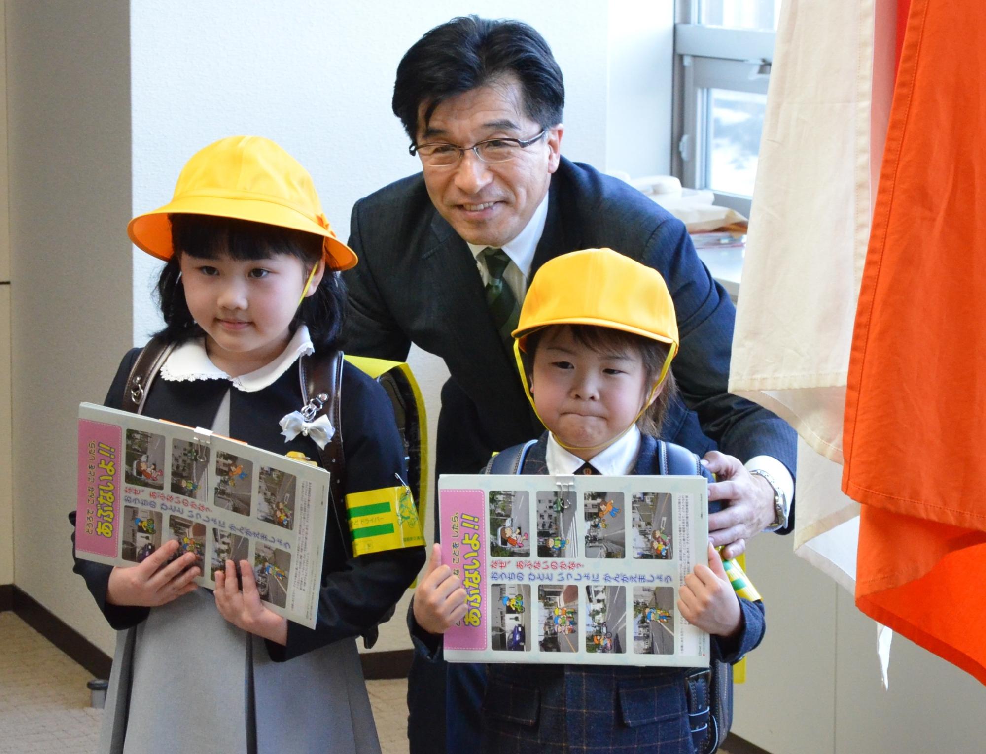 市長がランドセル姿の子供2人の肩に手を置き、3人で並んでいる写真