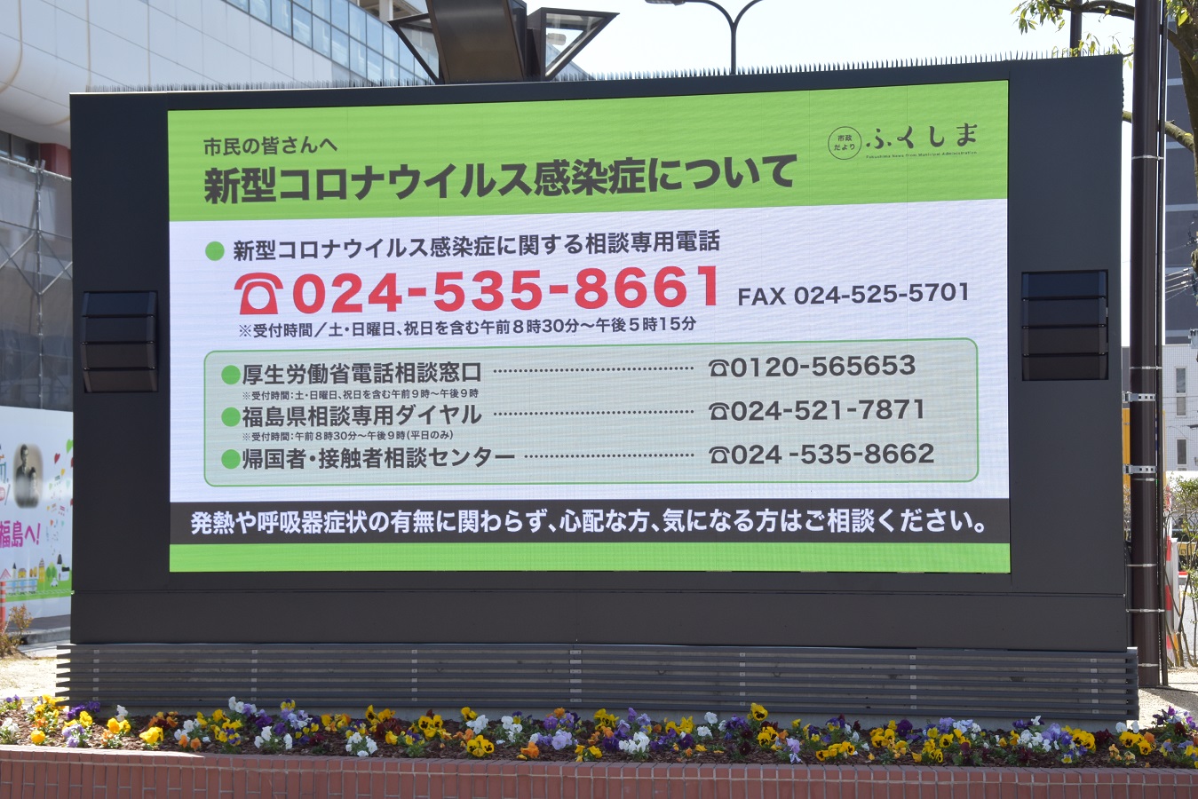 花壇の前に設置されたマルチビジョンに新型コロナウイルス感染症についての情報が映し出されている写真