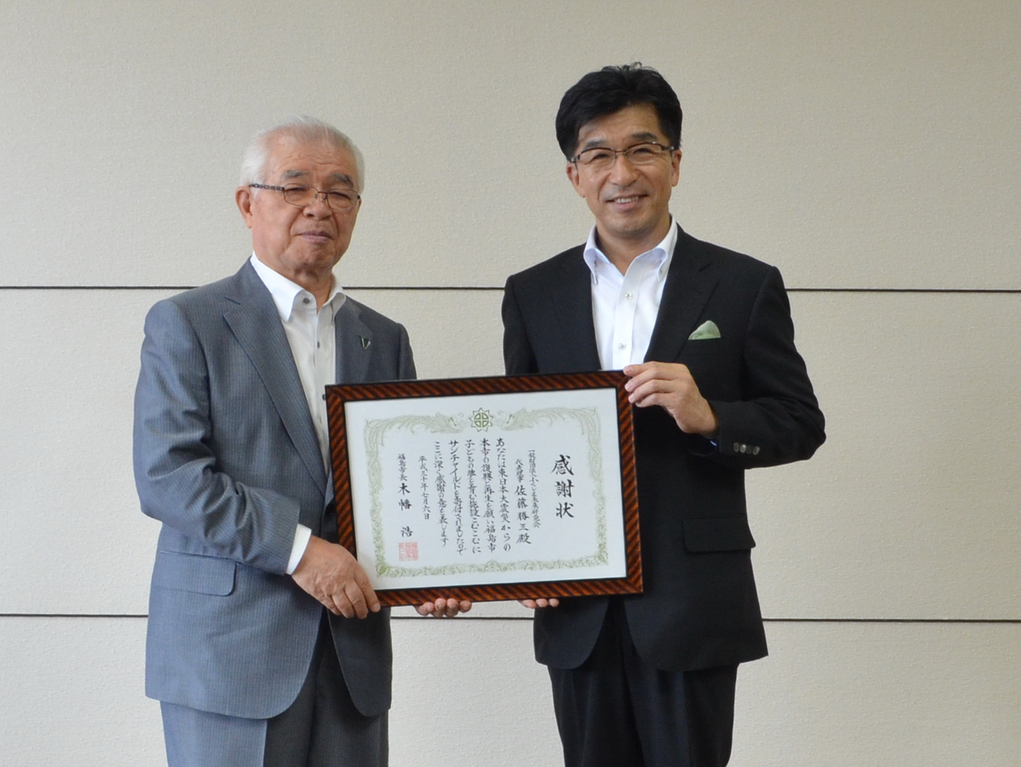 グレーのスーツ姿の男性と市長が並んで立ち、一緒に感謝状を持って写した記念写真