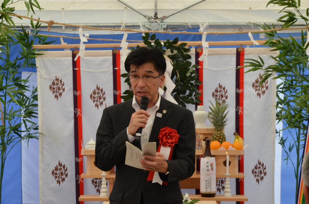 テントの中に置かれた祭壇の前に立ち、マイクを持って挨拶をする市長の写真