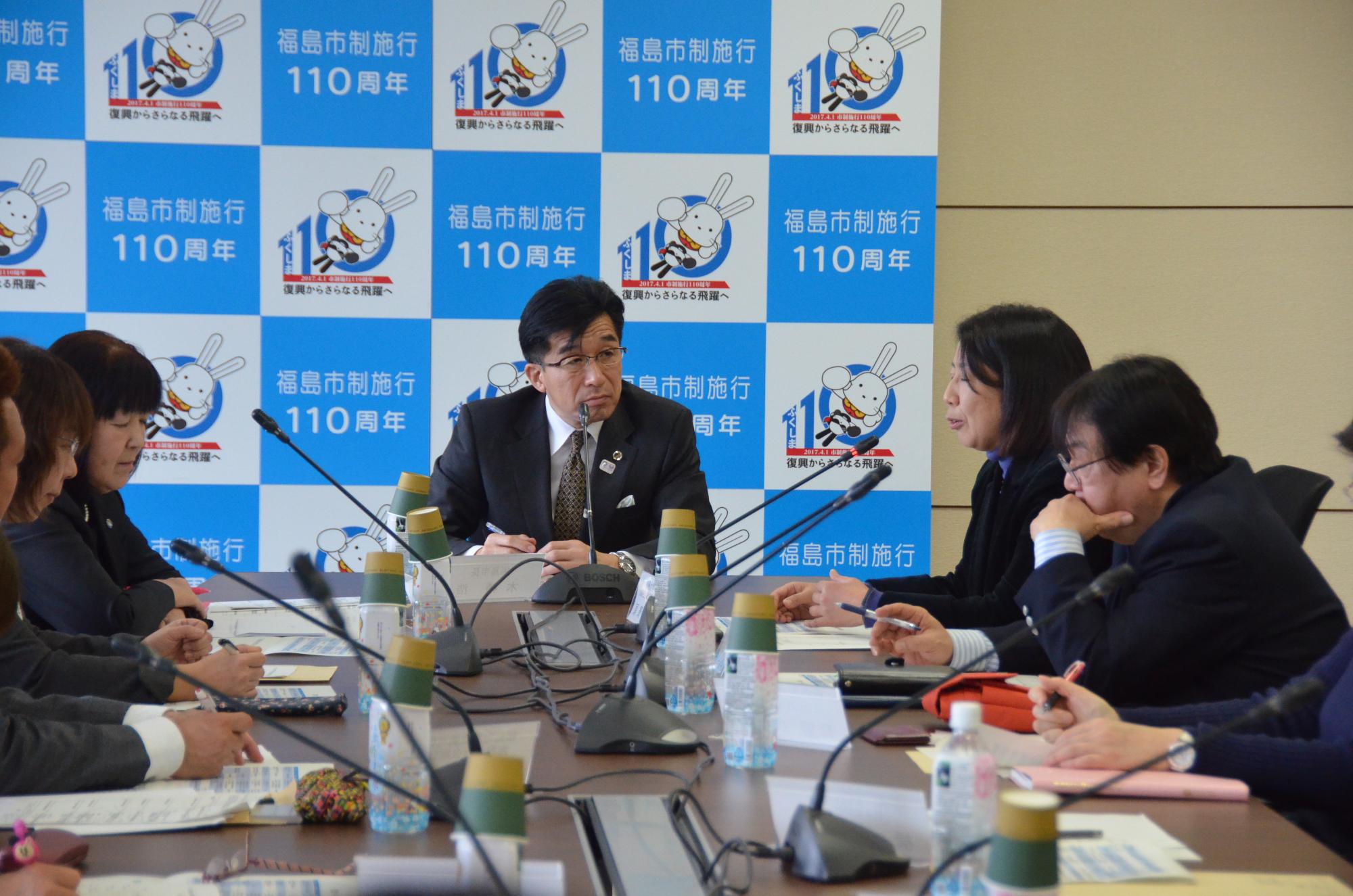 市長と関係者が席に座り議論している写真
