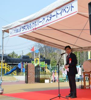 「ふくしま児童公園SFCももりんパークスタートイベント」と書かれた横断幕が掲げられたテントに赤いカーペットが敷かれ、テントの下のスタンドマイクで市長が話をしている写真