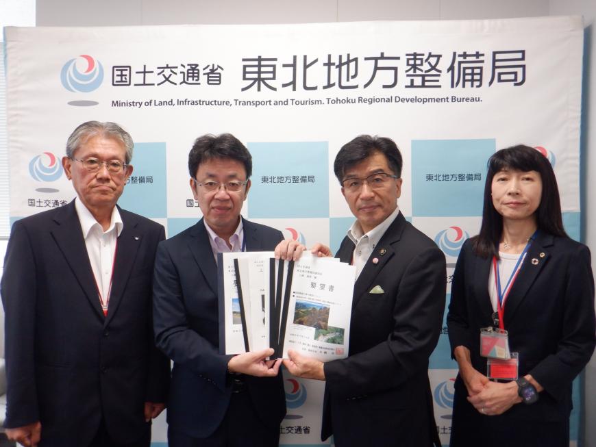 東北地方整備局のバックパネルの前で、市長と男性で4冊ほどの要望書を持ち、両脇に男性と女性が立っている写真
