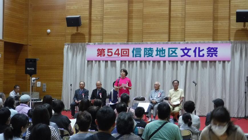 第54回信陵地区文化祭の舞台で中央のマイクの前にピンクの服を着た女性が立っている写真