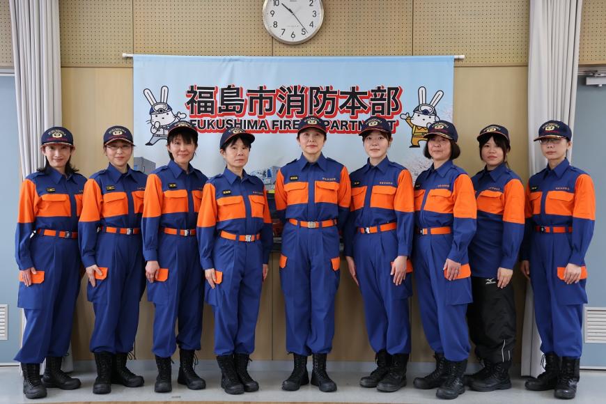 「福島市消防本部」の横断幕の前に9名に女性隊員達が並んだ集合写真