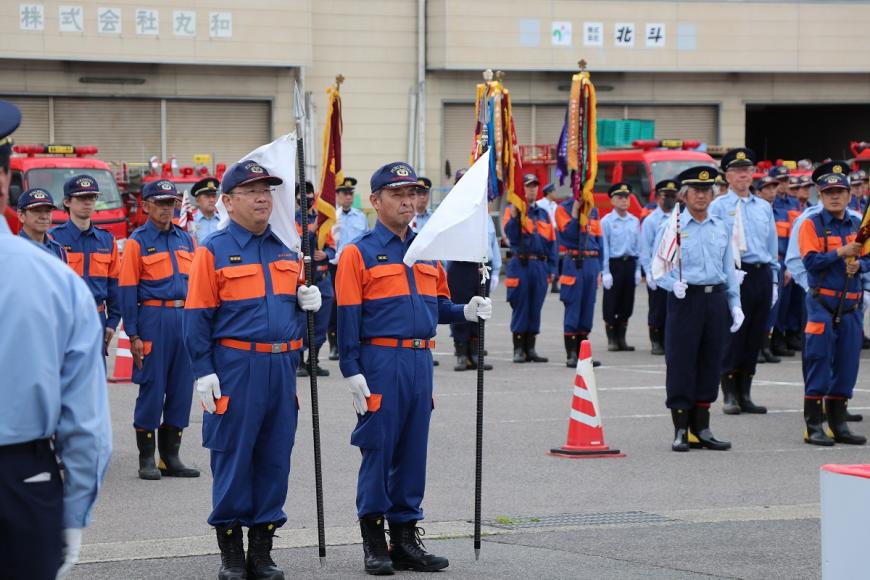 紺色の活動服を着た隊員が整列し真剣な表情で前を見ている写真