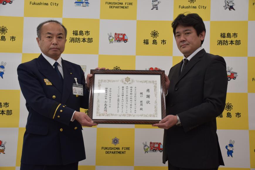 七島消防長と樋口照周さんが感謝状を持っている写真