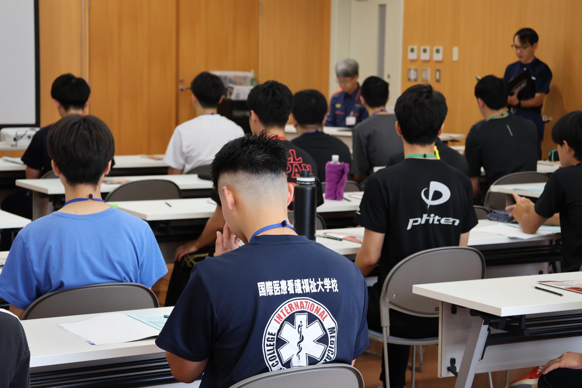 会議室内で事前説明を自席で聞く参加者の写真