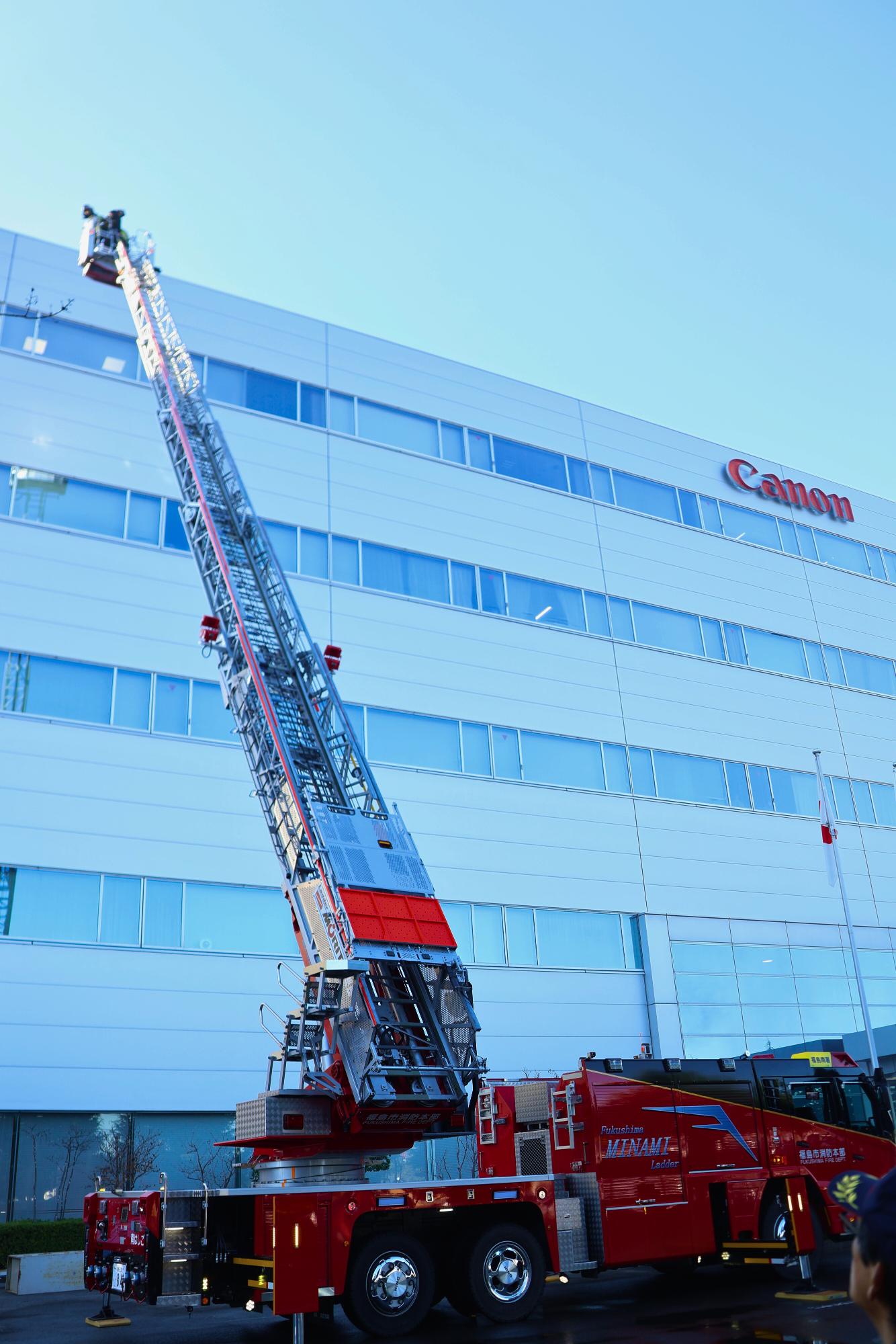 消防職員がはしご車で建物屋上にいる要救助者を救出している写真