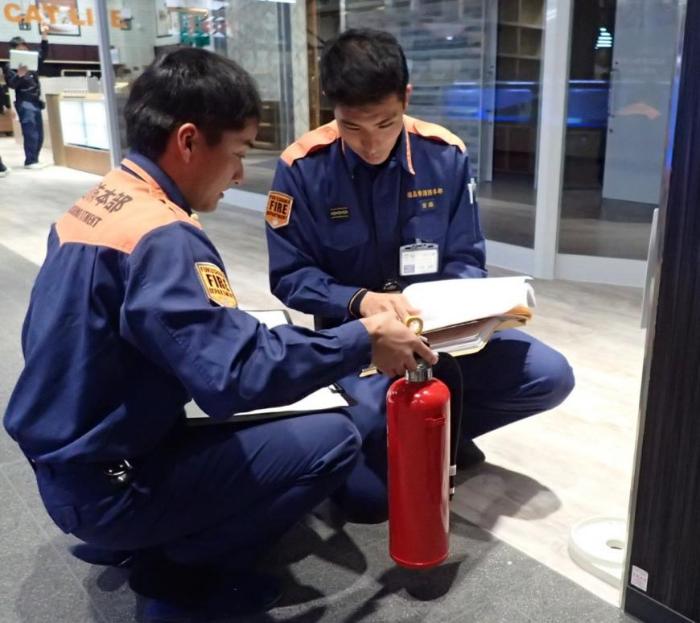 消防隊2人で消火器の点検をしている写真