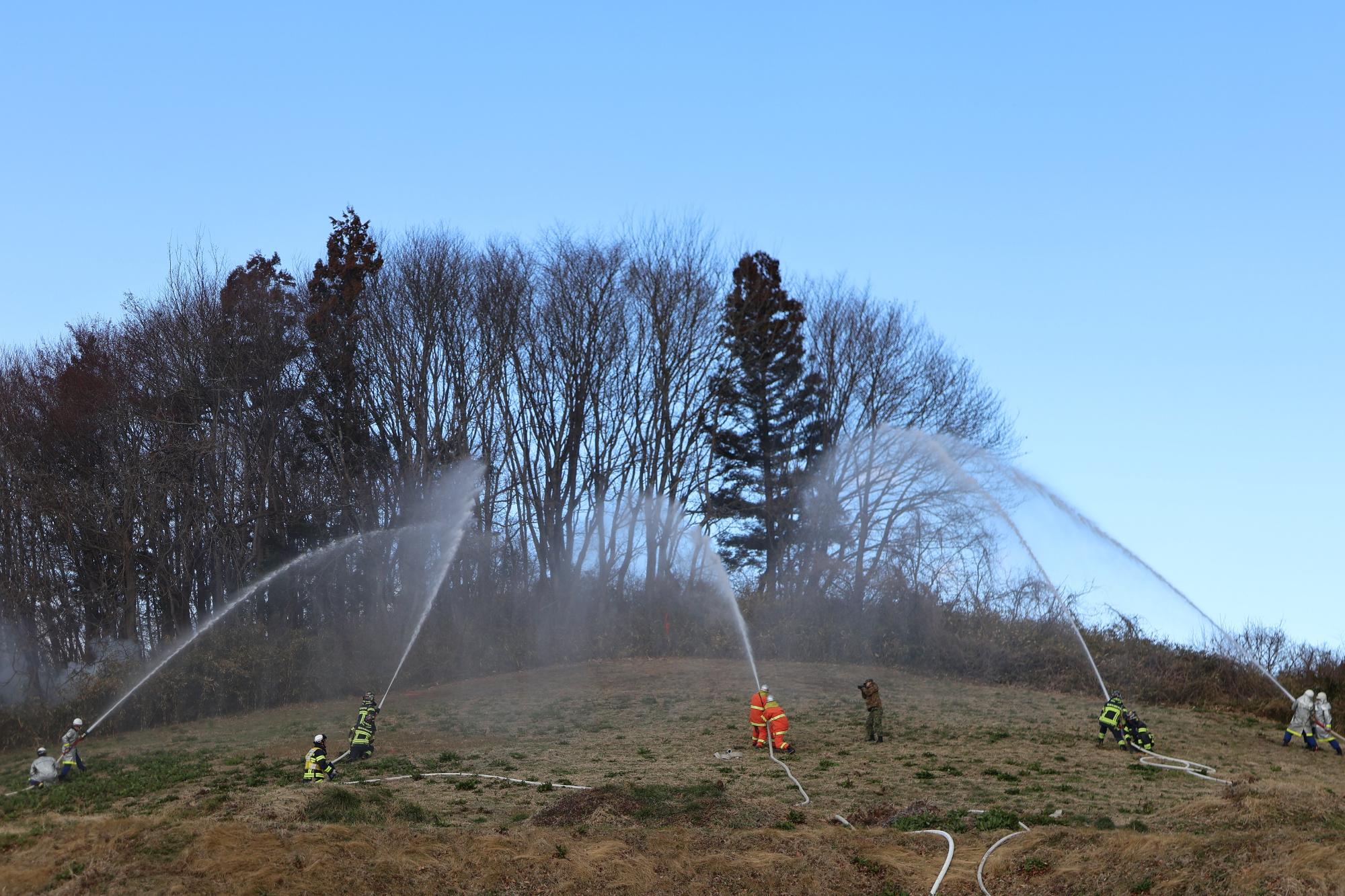 消火隊が5か所から一斉に山に向かって放水している写真