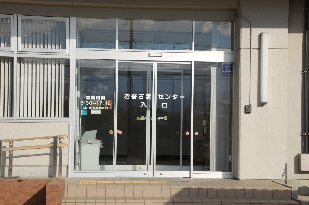 「お客さまセンター 入口」と書かれたガラス張りの正面玄関前を写した写真