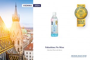 福島市のミネラルウォーター「Fukushima No Mizu (ふくしまの水)」のボトル写真が配置され、右上にモンドセレクション2024年の金賞「GOLD AWARD」のエンブレムが、左側にはオーストリア・ウィーンの教会の尖塔と街並みの写真が縦に並べられたレイアウトの広報用グラフィックの写真