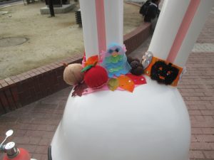 落ち葉、茶色のドングリ、赤いリンゴ、カボチャなど秋のモチーフの飾りが頭にたくさんつけられたももりんウォーターの後ろ姿を写した写真