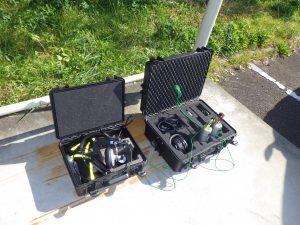 黒いケースが2つ並んで開かれており、左側のケースには黄色と黒のケーブルが付いた大型のヘッドホンが入っている「漏水探知器」、右側のケースには各種センサーやヘッドホンなどの機材が収納された「相関式漏水探知器」の写真