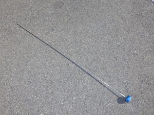 地面に置かれた細長く伸びた金属製の棒で、先端に青い球状の部品が付いている音聴棒の写真