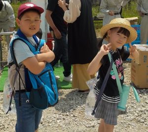 水の入った背負い式給水袋を背負った男の子と女の子がカメラ目線でポーズをとっている写真