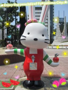 「Enjoy the peaches of Fukushima City」の文字や星、ハートなどの装飾的なエフェクトが施され、晴れた日の屋外で耳に桃をつけて街中に立つももりんウォーターの写真