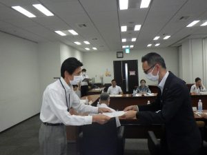 会議室で清野一浩水道事業管理者から村上崇広委員に委嘱状を手渡ししている様子の写真