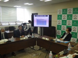 棒グラフが表示されているディスプレイを見ながら話をしている会議風景の写真