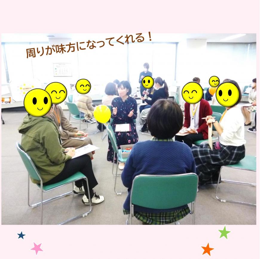 「周りが味方になってくれる!」の文字、グループごとに分かれて輪になって椅子に座ってメモを取りながら話を聞いている参加者の写真