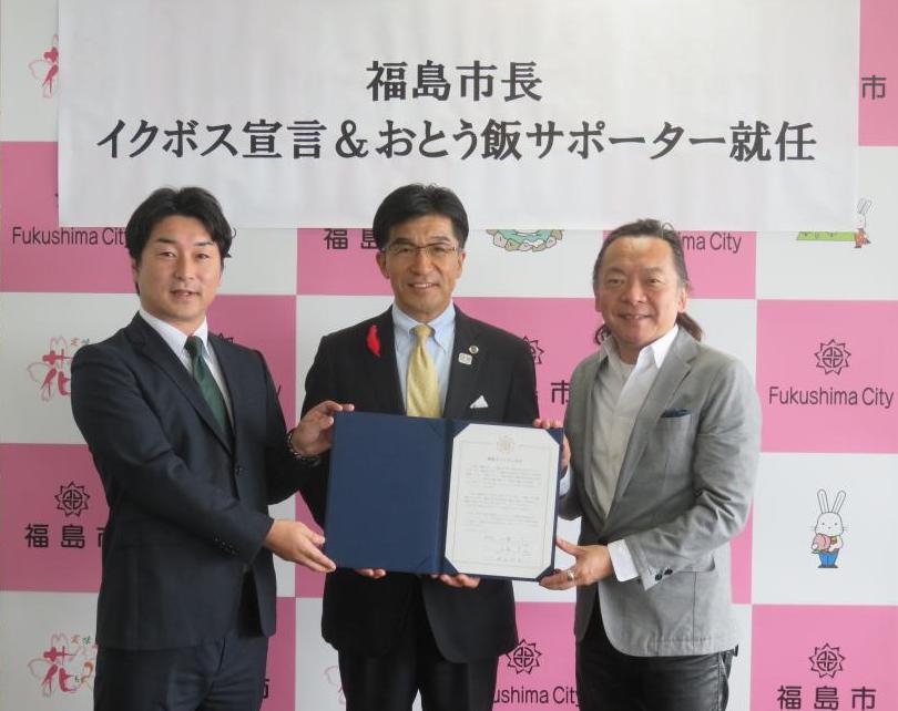 市長を中心に男性2名が並び3人で宣誓書を持ち記念撮影をしている写真