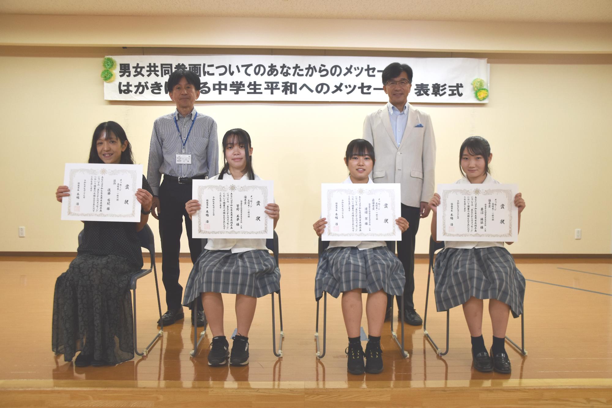 メッセージ高校生一般の部の入賞者が座り賞状を見せながら笑顔で記念撮影をしている写真