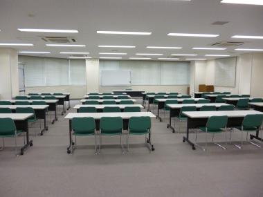 長机に椅子が3脚ずつ設置され4列に並べられている大会議室の写真