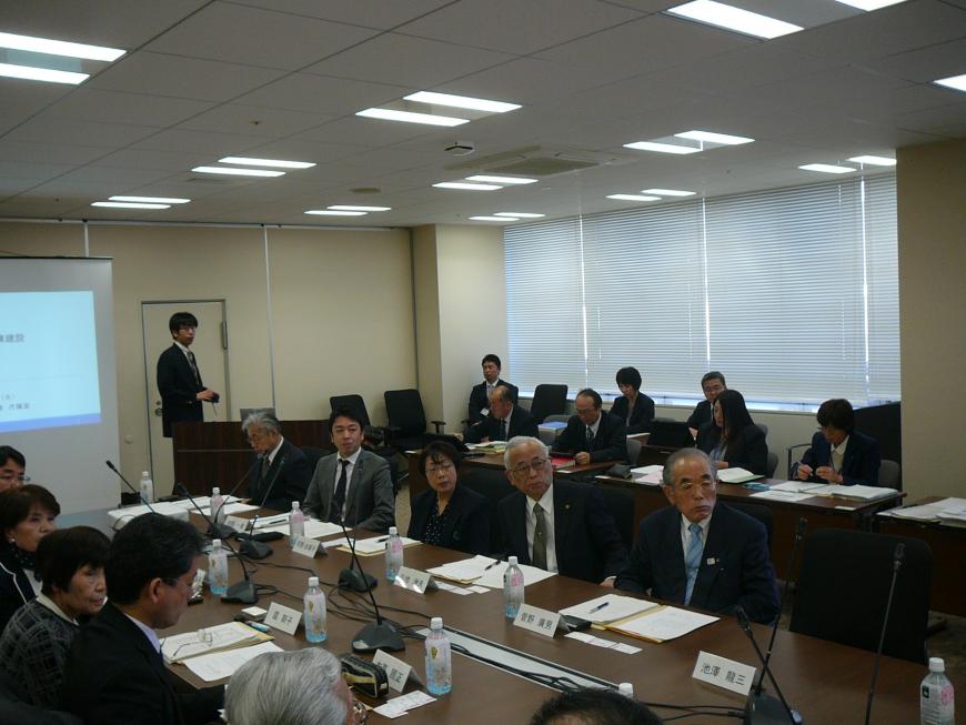 長机と椅子が設置された会場で机に資料や飲み物が置かれ懇談会が行われている全体の様子の写真