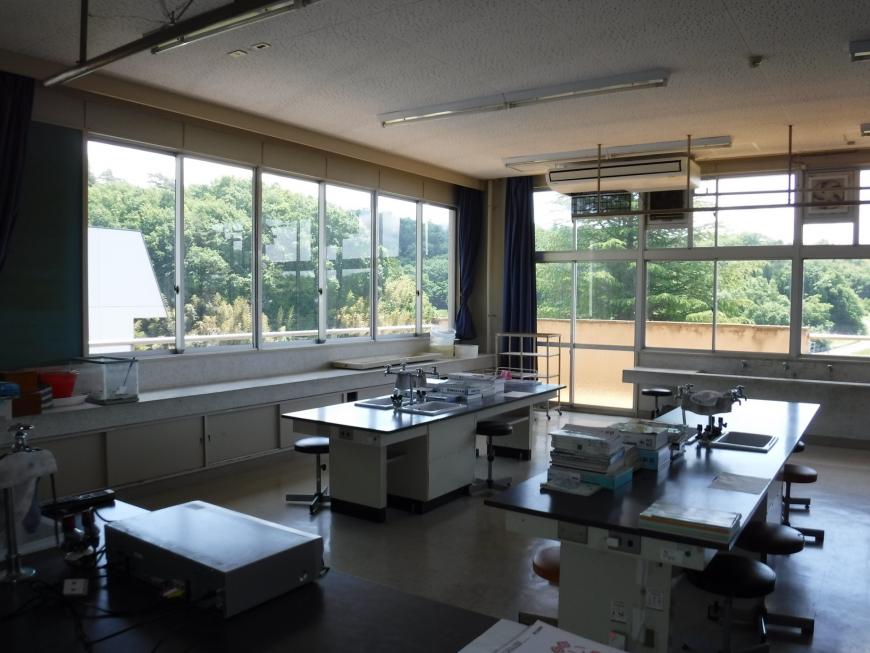 窓に覆われた部屋に換気扇や手洗い場などが設置され、蛇口の付いた実験台のような机が2つ並べられた教室の写真