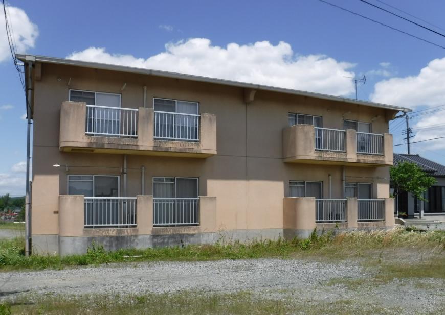 2階建てのベージュ色の外壁でベランダ側を写した飯野町教職員住宅の写真