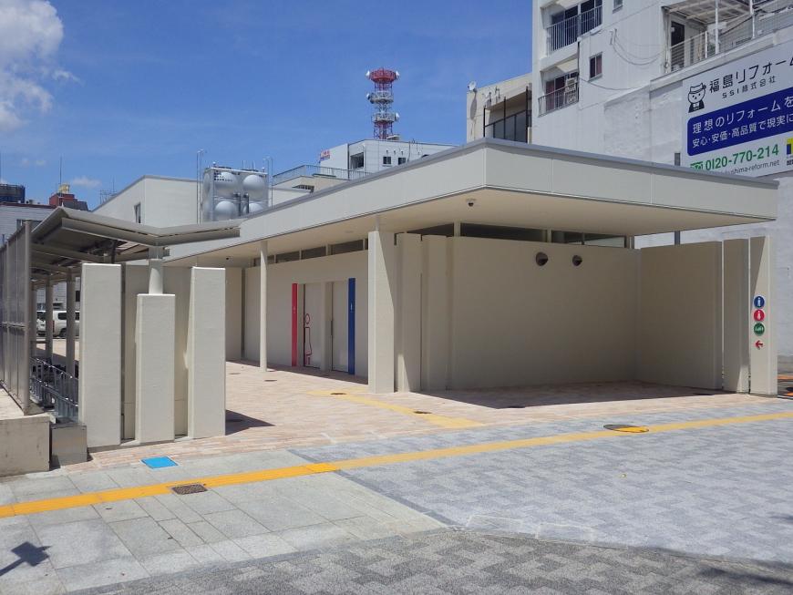 白を基調とした外壁で中央にピンク色の女性用トイレと青色の男性用トイレのドアが設置された写真