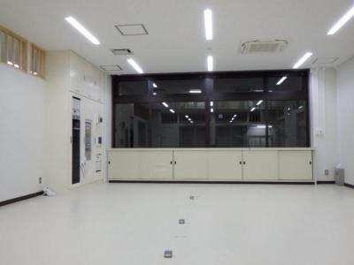 白壁で奥に収納ボックスが設置された上に大きな窓ガラスがある、物が何も置かれていない室内の写真