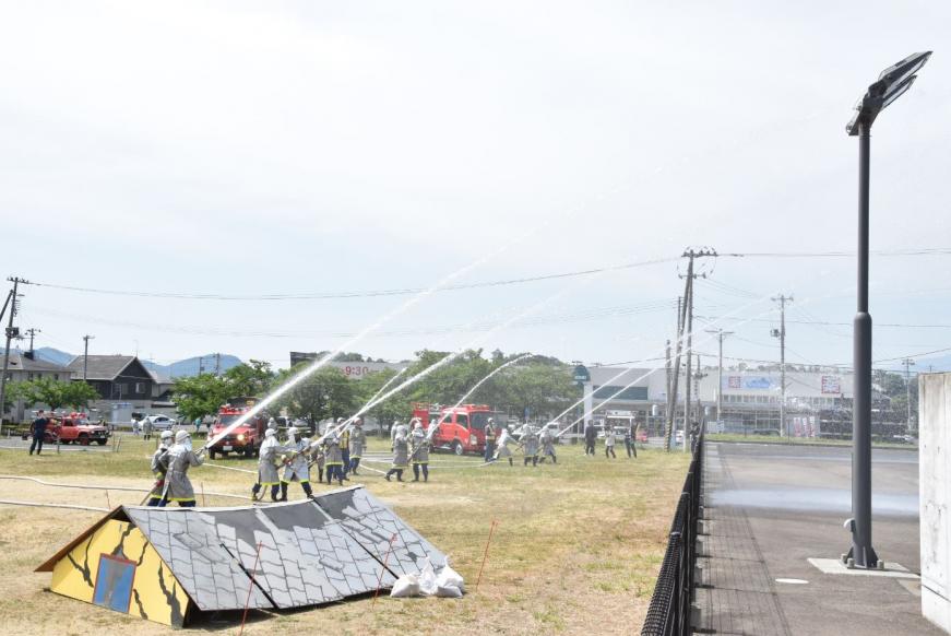 横一列に並んだ消防団の方々が一斉に上に向かって放水している写真