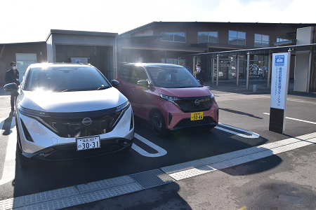 電気自動車充電ステーションに白色の普通車とピンク色の軽自動が2台駐車している写真