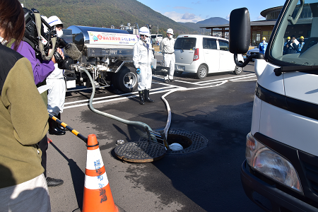 地下貯留タンクのマンホールに管をのばし給水車に送水を行っている様子の写真