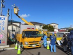 電源車が停まっており、高所作業車に乗った作業員の方が作業をしている様子の写真