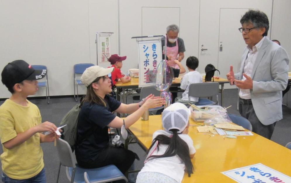 子供たちがきらきらシャボン玉の遊び方の指導を受ける様子の写真