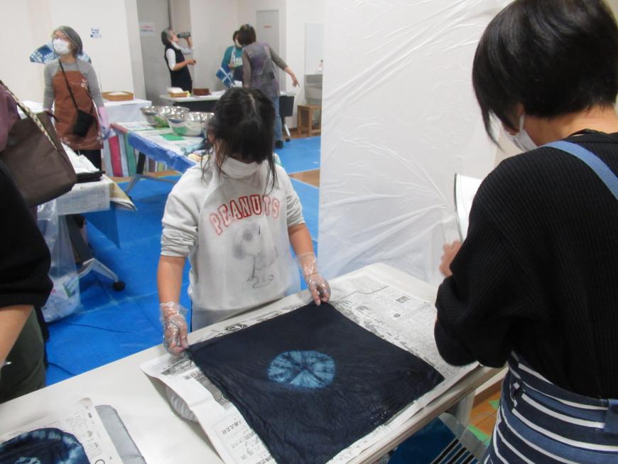 机の上に藍染の作品を置いて眺めている女の子の写真