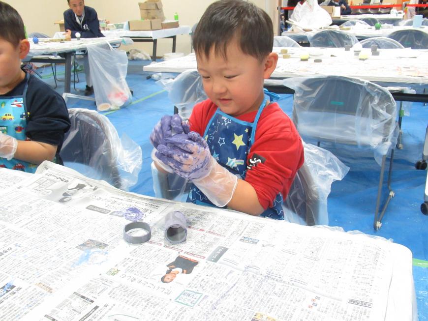 エプロン姿の男の子がビニール手袋をしながら色付けをしている様子を写した写真