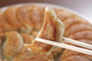 きつね色にこんがり焼いたふくしま餃子を箸で持っている様子をアップで撮影した写真