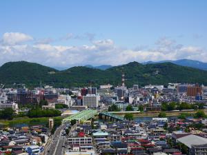 青空のした福島市の町並みが広がり、遠くには山並みが連なっている写真
