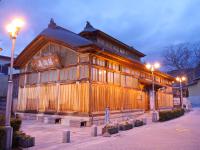 薄暗くなってきて街灯の光が灯った奥に建つ、日本最古の木造建築様式の鯖湖湯の建物外観の写真
