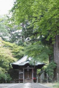 大きな木々に囲まれた文知摺観音の境内に佇む観音堂の写真