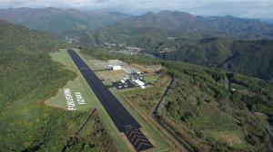 山に囲まれた中央に農道離着陸場が整備されたふくしまスカイパークを上空から撮影した写真