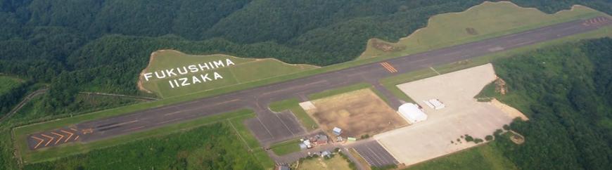山に囲まれた中央に農道離着陸場が整備されたふくしまスカイパークを上空から撮影した写真
