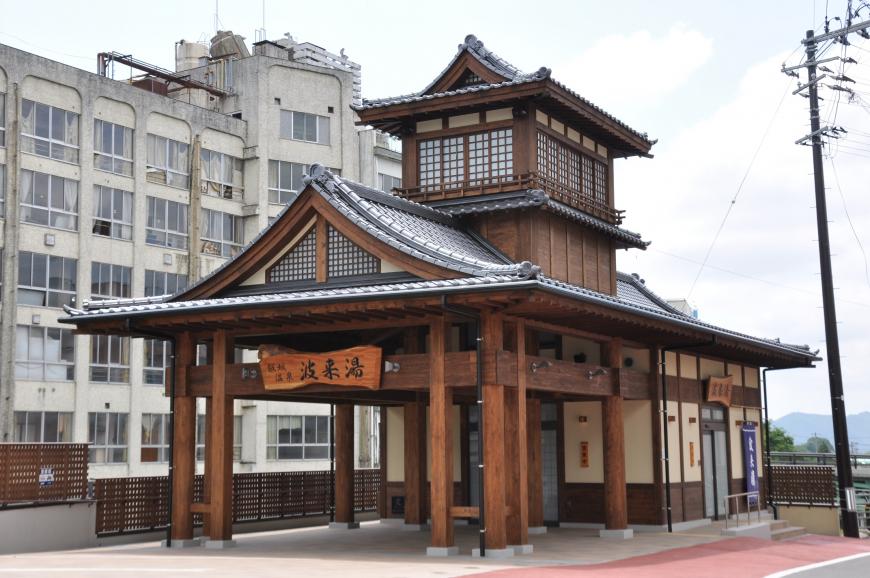 「波来湯」と書かれた木製看板が入り口に設置された茶色の外壁のの建物外観の写真